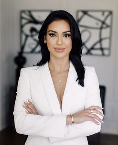 a woman in a white suit with her arms crossed