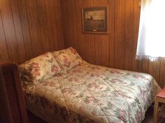 a bed in a room with wood paneling and floral bedspread on it