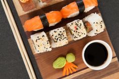 sushi and chopsticks are arranged on a wooden board with a cup of coffee