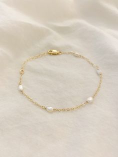 5-PEARL BRACELET This dainty bracelet has tiny natural shaped pearls on a string of 14K Gold Filled or Sterling Silver chain. Each Pearl is hand wrapped. This bracelet looks gorgeous layered with other gold bracelets, or looks beautiful and minimal worn alone. Gold Filled and Sterling Silver are hypoallergenic and tarnish resistant. △ 3-4mm freshwater Pearls △ Dainty 14K Gold Filled Chain or Sterling Silver with a quality 14K Gold Filled or Sterling Silver lobster clasp. △ Choose your length See Delicate White Bracelets For Bridesmaids, Delicate White Bracelet For Bridesmaid, Dainty White Chain Bracelet With Extender, Delicate White Chain Bracelet, Dainty Yellow Gold Beaded Wedding Bracelet, Delicate Chain Bracelet With Extender, Dainty Bracelet With Adjustable Chain For Bridesmaids, Dainty Bracelet With Adjustable Chain As Bridesmaid Gift, Delicate Bracelet With Adjustable Chain For Bridesmaids