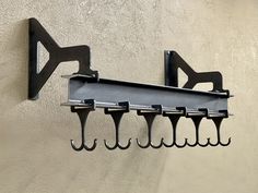 there is a coat rack on the wall with five hooks attached to it, and one hook has four clips