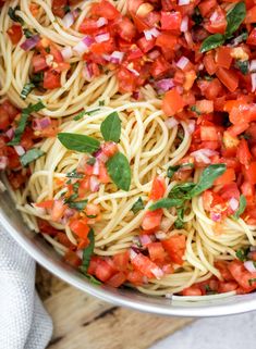 a bowl filled with pasta and vegetables on top of a wooden table