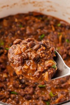 a spoon full of chili and beans in a pot