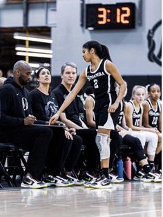 the women's basketball team is sitting on the bench and looking at their coach