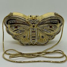 Really Beautiful And Rare Vintage Judith Leiber Brushed Gold Butterfly Minaudiere Bag With Swarovski Crystals And Cabochon Stones Of Red, Black And Green. Closure Topped With 2 Cabachon Stones. Genuine Gold Leather Interior. Length ~ Approx 6 1/4” Depth ~ Approx 3 3/4” Chain ~ Approx 38” In Excellent Condition With Barely If Any Signs Of Wear! No Missing Crystals Or Stones. Please See Photos. Comes From A Smoke Free Home. Comes With Judith Leiber Dust Pouch.