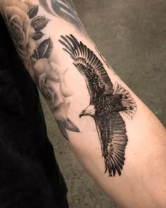 an eagle and roses tattoo on the arm