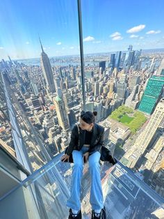 a man sitting on top of a tall building looking down at the city below him