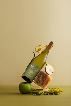 a bottle of wine, apple slices and honey on a table with a comb in it