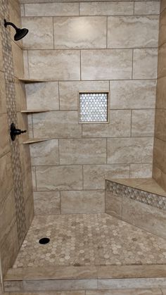 a walk in shower sitting next to a tiled wall and floor covered in beige tiles