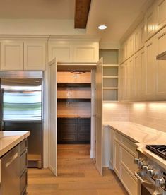 an empty kitchen with white cabinets and stainless steel appliances, along with wood flooring