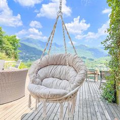 a hanging chair on a wooden deck with mountains in the background