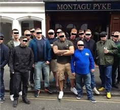 a group of men standing in front of a building with their arms around each other