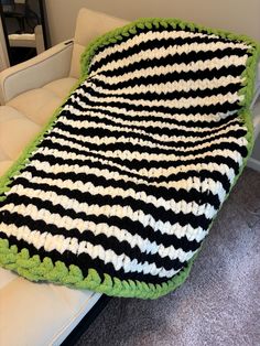 a crocheted blanket sitting on top of a couch next to a white chair