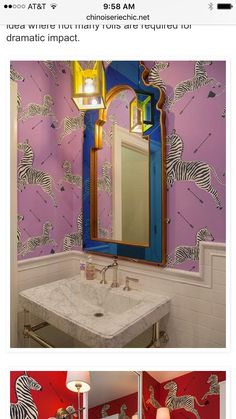 a bathroom with purple and blue wallpaper has a mirror on the wall above it