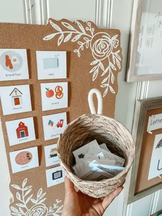 a person holding up a basket filled with cards and magnets in front of a bulletin board