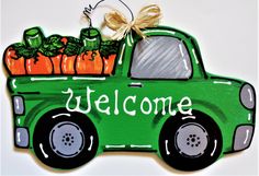 a green truck with pumpkins in the back and welcome sign on it's side