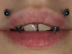 a woman's mouth with two metal spikes on it