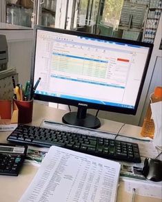 a computer monitor sitting on top of a desk next to a calculator and keyboard