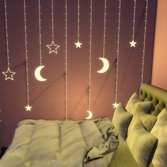 a bed with white stars and moon lights hanging from the ceiling