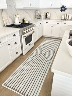 a kitchen with white cabinets and an area rug on the floor in front of the stove