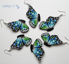 six blue and green butterfly earrings on white background