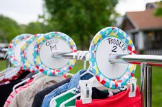 there are many different colored shirts hanging on the rack in front of some houses and trees