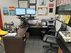 an office cubicle with two computer screens on the desk and yellow chairs in front of it