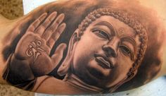 a tattoo on the arm of a man with a buddha face and hands in front of him