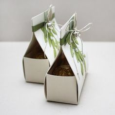 two white boxes with green leaves on them are sitting side by side in front of each other