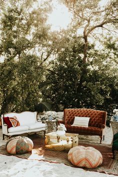 a living room with couches and pillows on the floor in front of some trees