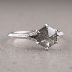 an engagement ring with a fancy diamond and pave set diamonds on the side, sitting on a gray surface