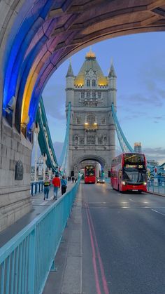 two red double decker buses driving over a bridge