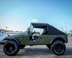 an army green jeep is parked in a parking lot