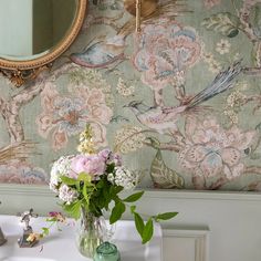 a vase filled with flowers sitting on top of a white table next to a mirror