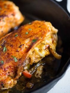 two pieces of chicken in a skillet on a stove top with some garnishes