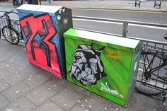 two trash cans with graffiti on them next to bicycles