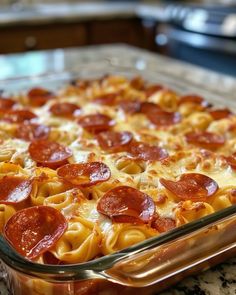 a pizza casserole with pepperoni and cheese in a glass dish on a counter