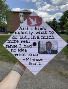 a hand holding up a graduation cap with the words michael scott on it and an image of a bird