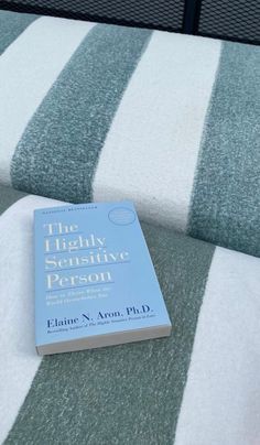 a book sitting on top of a bed next to a white and blue striped blanket