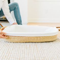 a person is sitting on the floor with a wicker basket in front of them