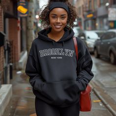 Cozy up in this Brooklyn hoodie and show off your love for the city that never sleeps. Featuring a bold red and black retro font, the word "Brooklyn" across the front makes a statement while still being a comfortable and versatile everyday wear.  Made with a soft and durable blend of materials, this hoodie will keep you warm and comfortable no matter the season. The classic design and relaxed fit make it perfect for any occasion, whether you're running errands around the city or just lounging at home.  Represent your favorite borough and add a touch of retro style to your wardrobe with this Brooklyn hoodie. It also makes a great gift for any Brooklynite or city lover in your life. So show off your pride and embrace the energy of Brooklyn with this must-have hoodie. Give a nod to the iconic Brooklyn Sweatshirt, Brooklyn Hoodie, New York Hoodie, New York Shirt, New York Sweatshirt, Sweatshirt Graphic, Cotton Polyester Fabric, Retro Sweatshirts, Black Retro