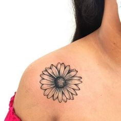 a woman's shoulder with a black and white flower tattoo on it