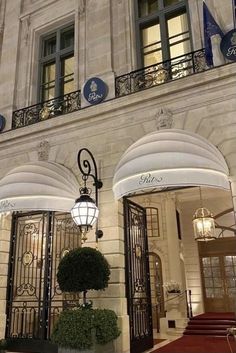 the entrance to an elegant hotel with wrought iron doors and chandeliers on either side