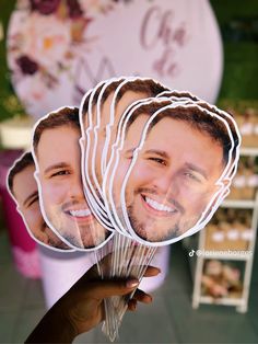 a person holding up some paper cut out of the faces of two men with flowers in front of them