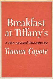 a book with an orange cover and white lettering on the front, which reads breakfast at tiffany's