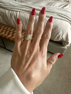 a woman's hand with red nail polish on it and a diamond ring in the middle