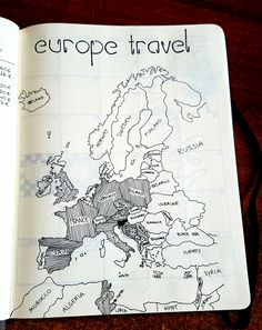 an open notebook with a drawing of europe on the cover and words written in black ink