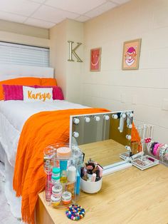 a bedroom with an orange blanket on the bed and various items in front of it