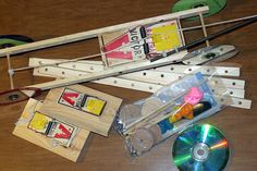 several pieces of wood and various tools on a wooden table with cd's, tape, and scissors