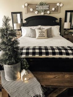 a black and white christmas bedroom with plaid bedding, potted pine tree, mirror frames and lights on the wall